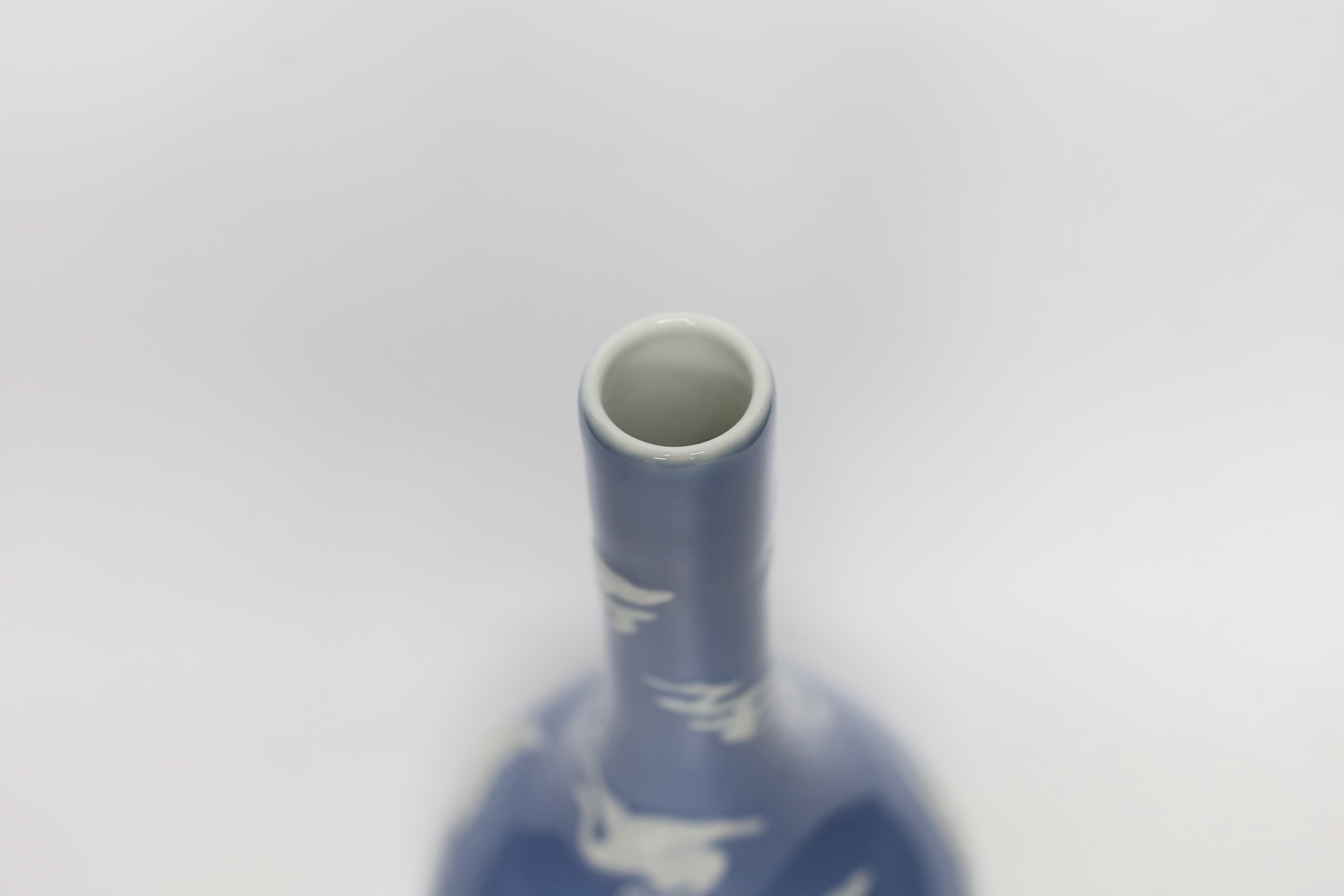 A Chinese blue bottle vase decorated in relief with cranes, on stand, 32cm high overall